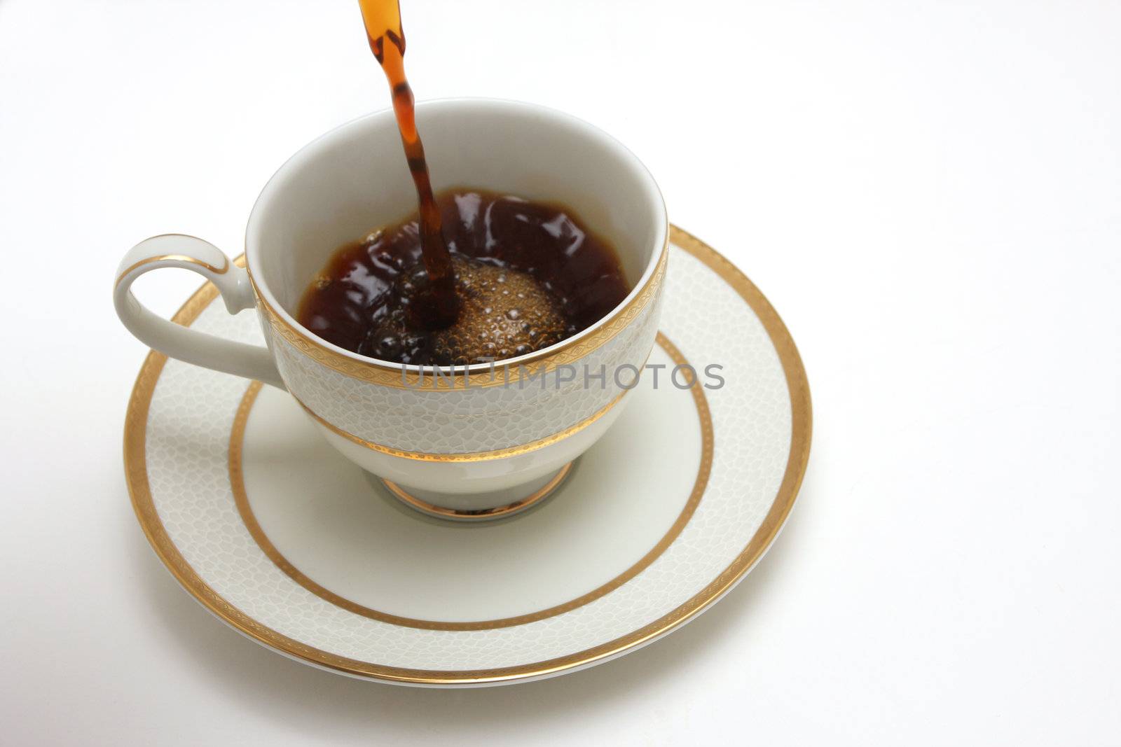 A sideview shot of a  cup of coffee isolated on white, coffe being poured into it