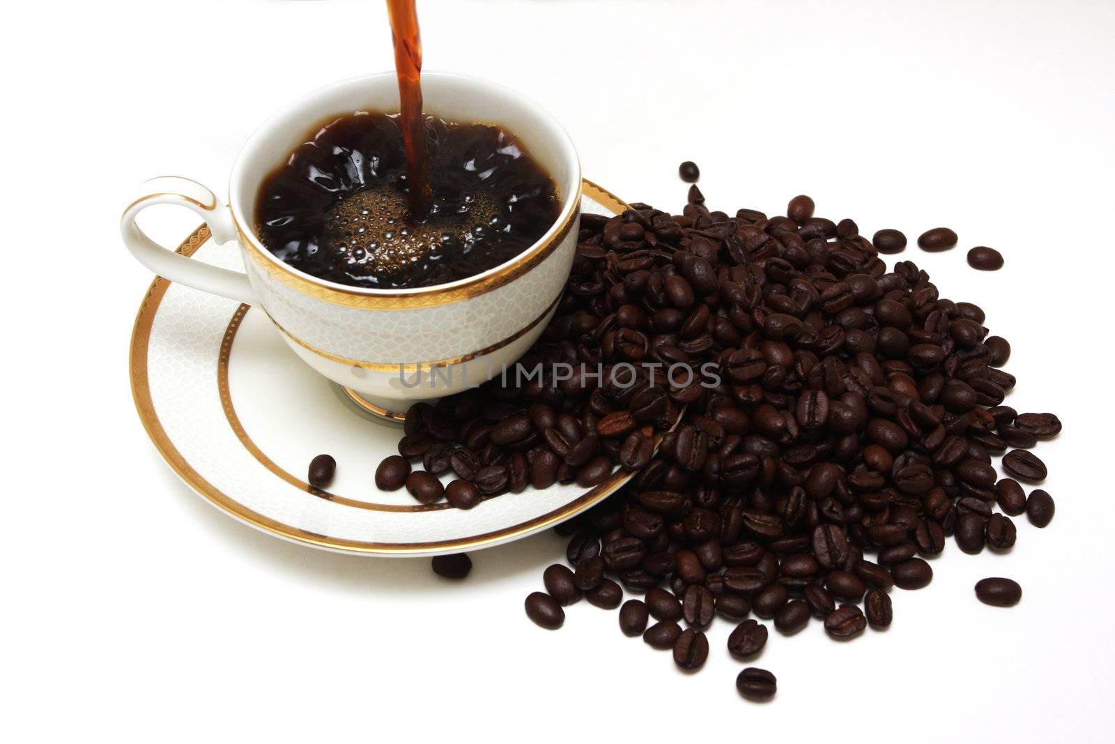 Coffee pouring into a cup with coffeebeans around, isolated on white