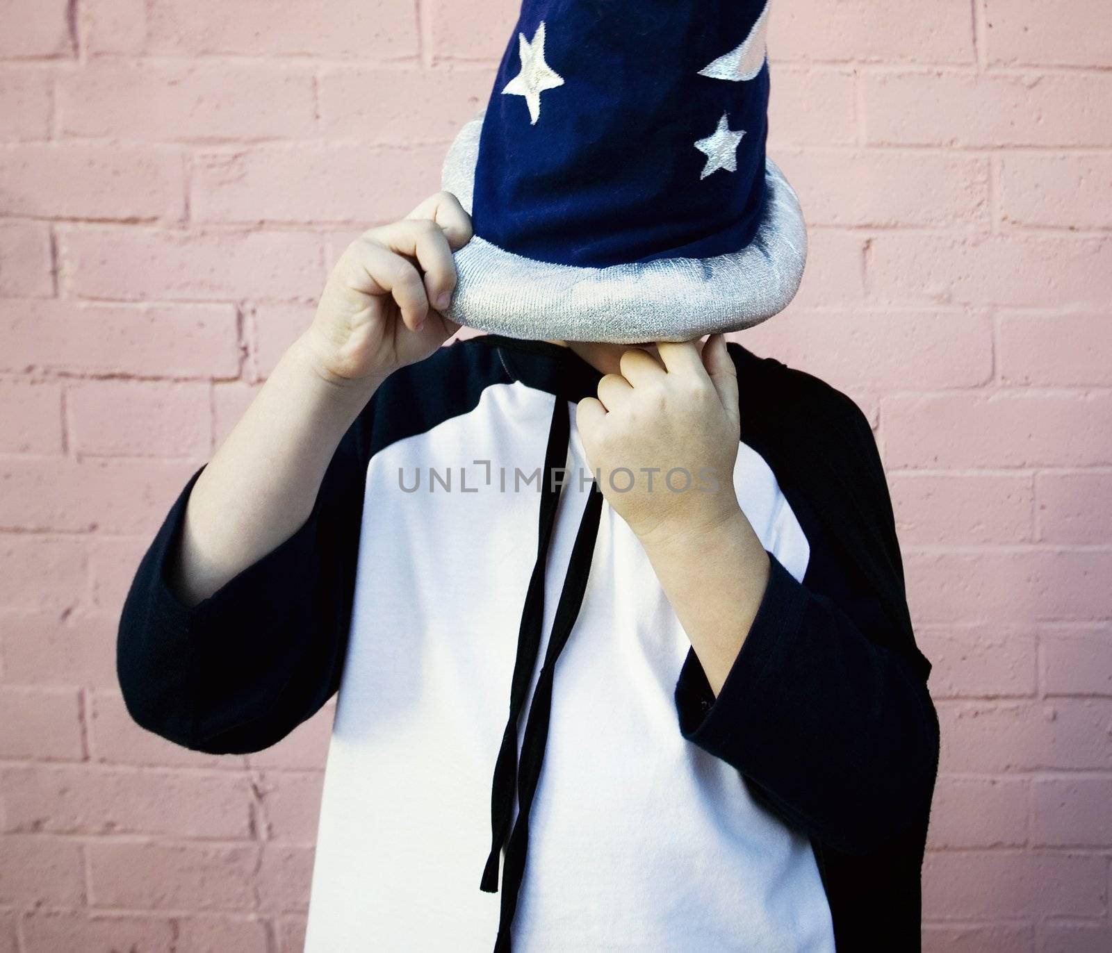 Young boy in a wizard costume and hat picking his nose