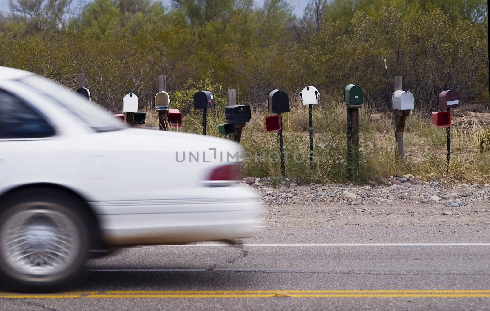 White car passes a set of rural mailboxes