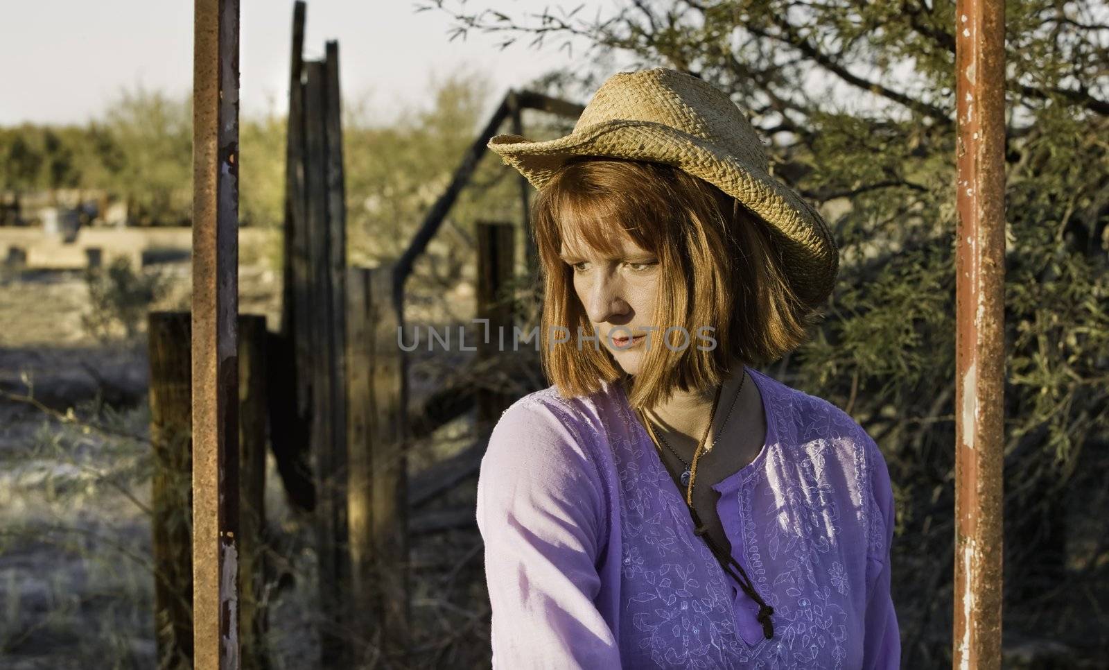 Woman wearing a cowboy hat in a rural setting.