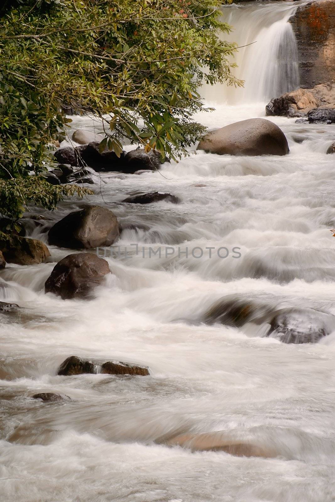 Small river in Costa Rica tumbles over rocks.  Slow shutter speed blurs the motion.