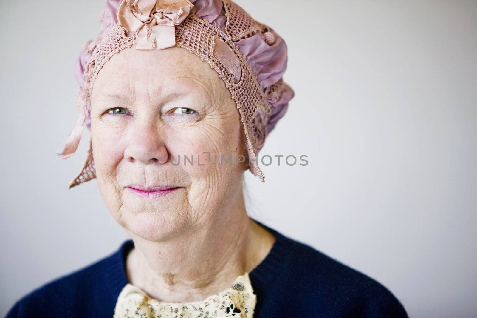 Senior smiling woman in the studio wearing a vintage hat and lace.