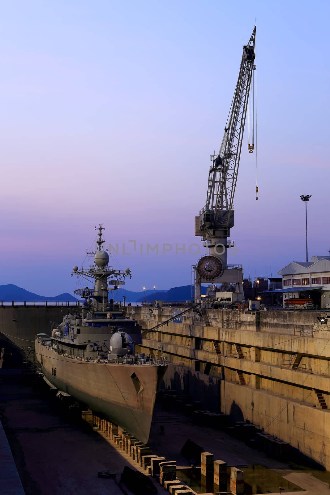 Crane near a covered dry dock at the shipyard by rufous