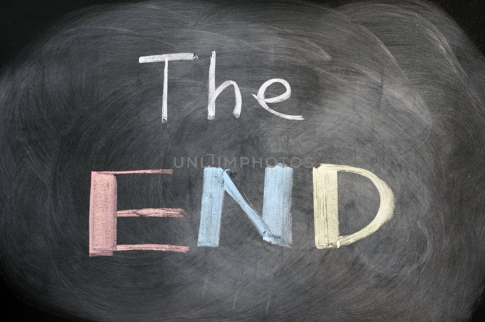 The end - handwritten with colorful chalk on a blackboard with eraser smudges 