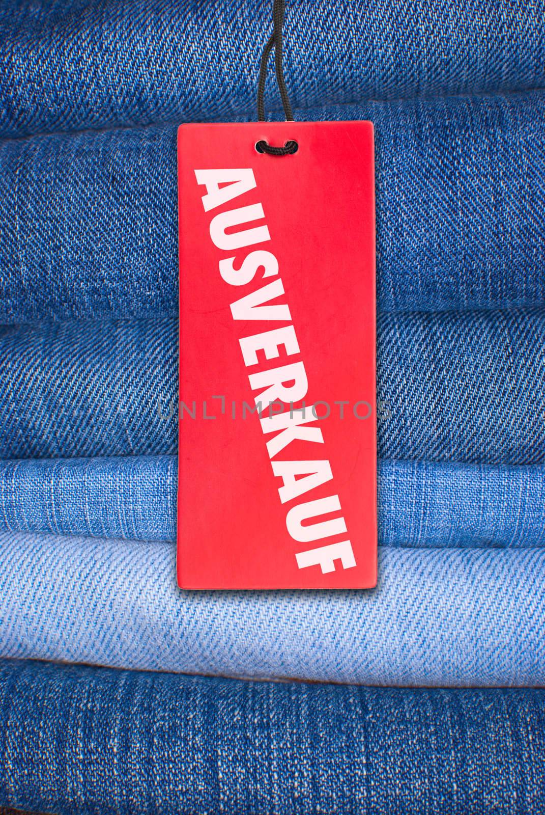 Red German Sale Sign With Stack of Blue Jeans in Background
