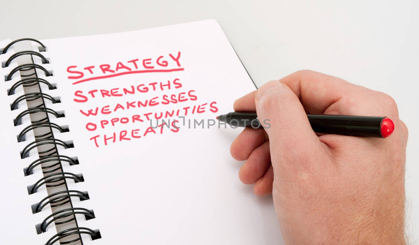 SWOT Analysis - Close up of Hand With Red Marker and Open Notebook