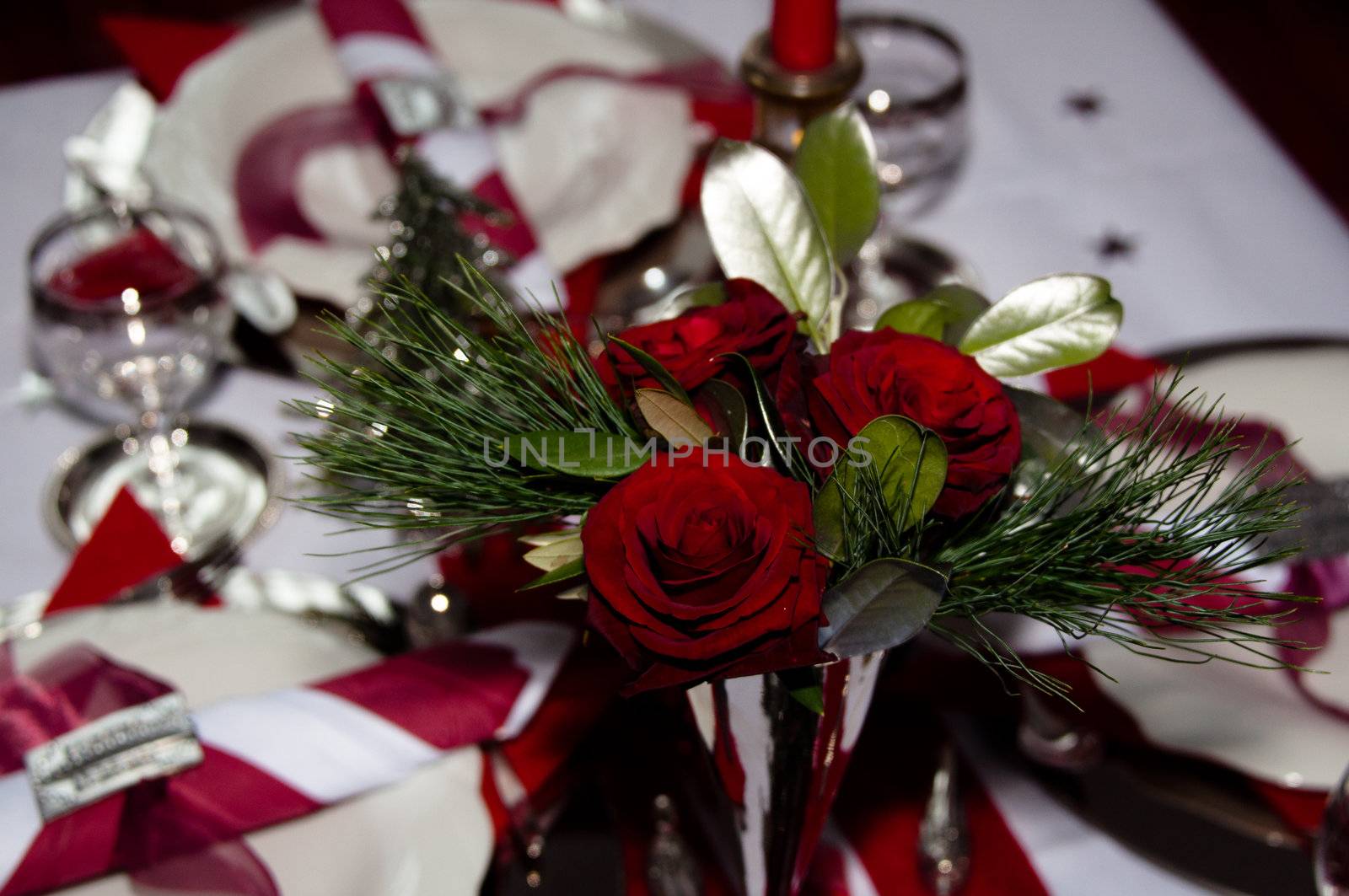 Christmas table with red decoration, napkins, roses, silver, christmas tree and candles