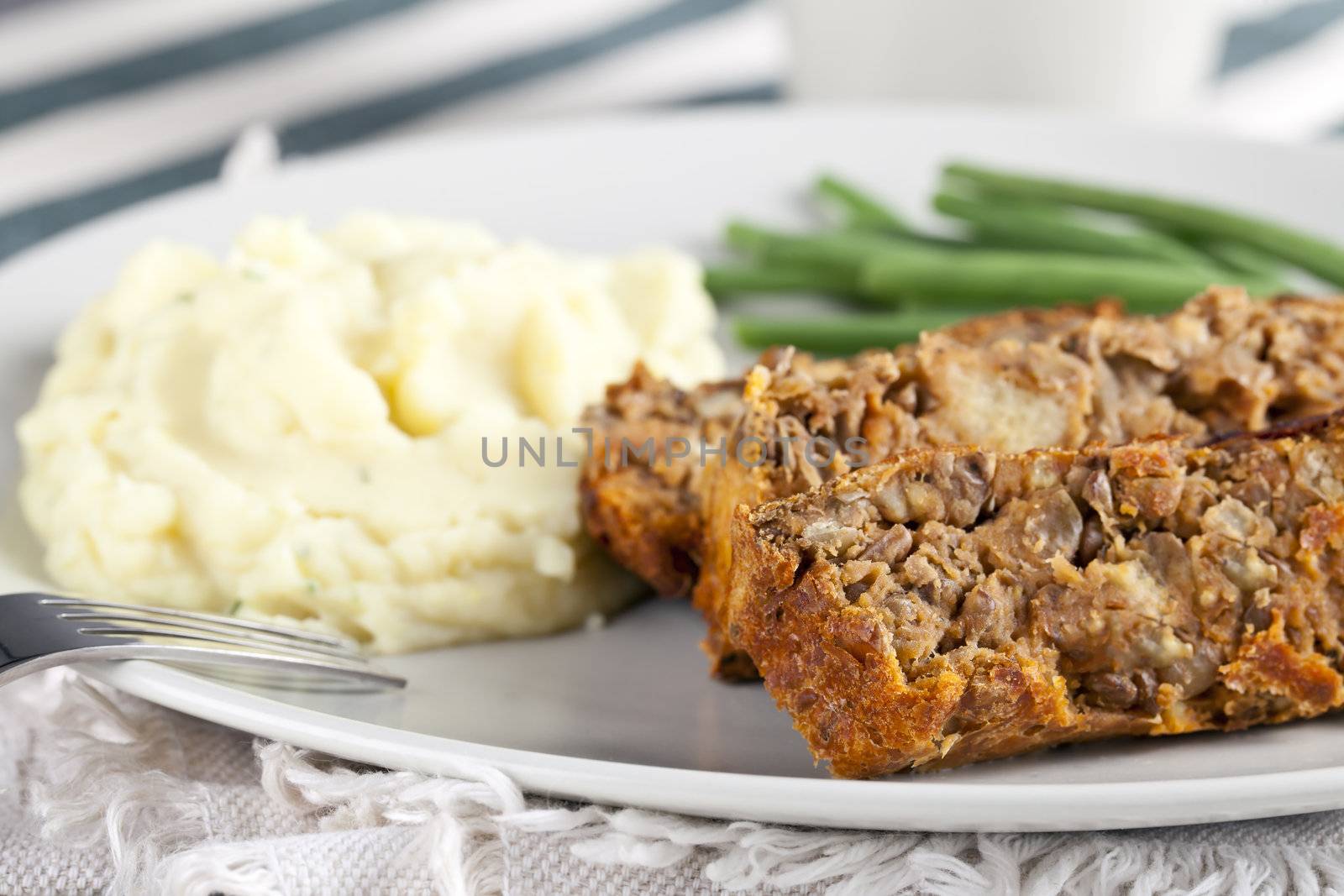 Vegetarian meal with lentil loaf, mashed potatoes and green beans.