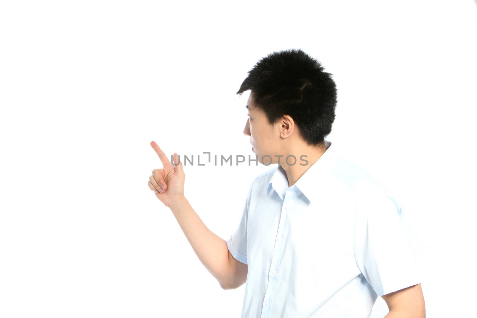Young Asian man in shirtsleeves turned away from the camera pointing behind him towards blank white copy space