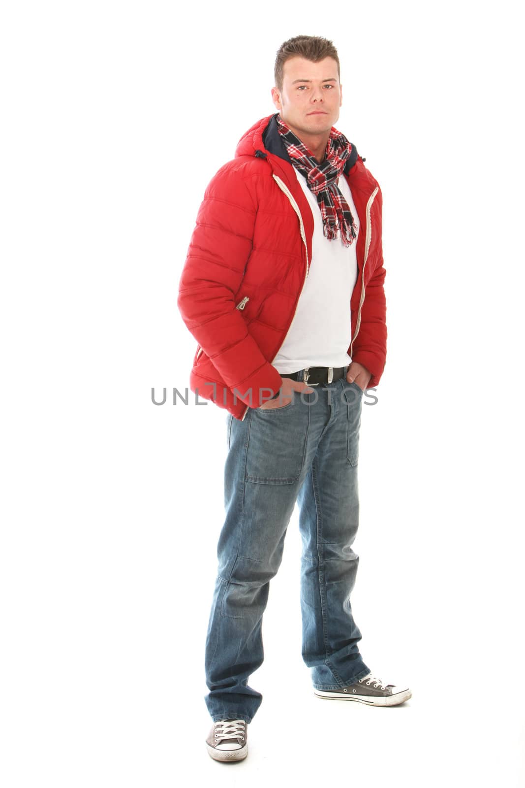Handsome casual young man in trendy winter clothing standing with his hands in his pockets looking at the camera isolated on white
