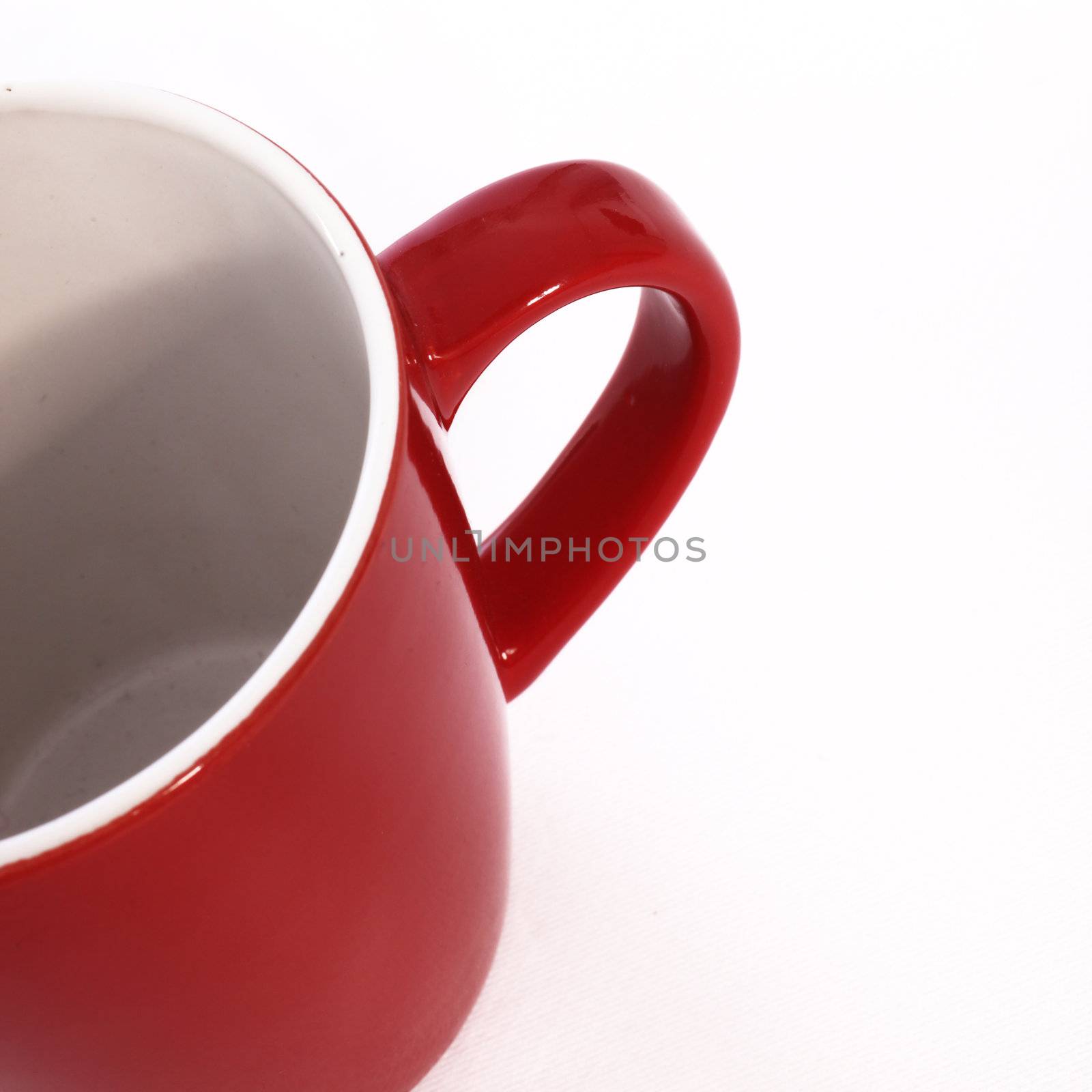 High angle partial cropped view looking inside an empty red ceramic coffee mug isolated on white