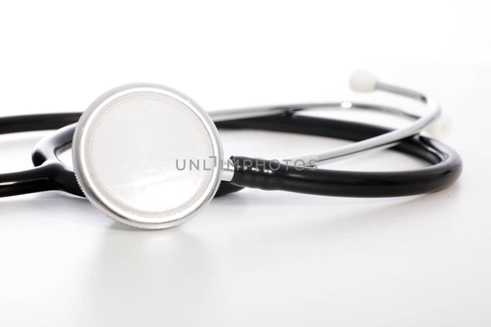 Coiled stethoscope with the disc to the fore on a white studio background in a healthcare concept
