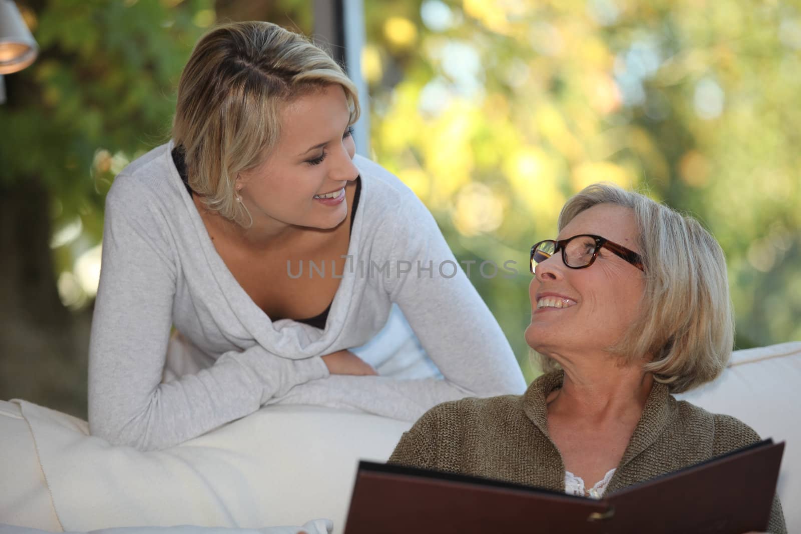 Young woman spending time with her grandmother by phovoir