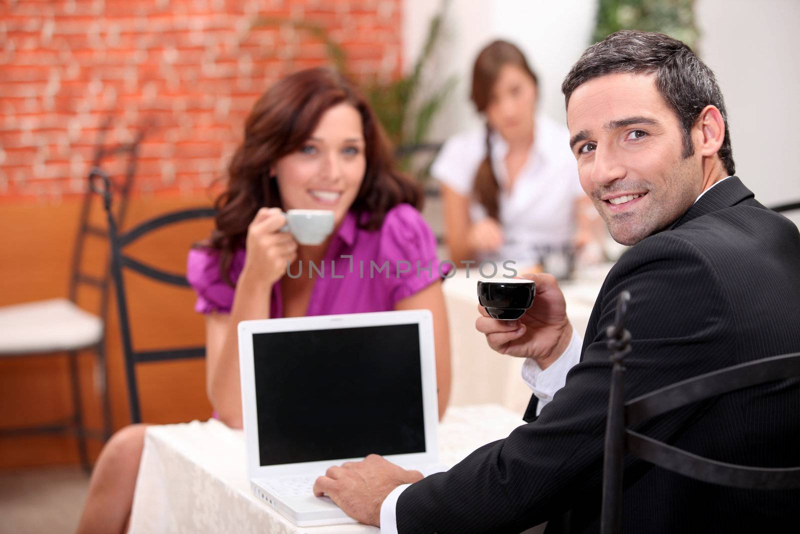 Man using a laptop computer in a cafe with a blank screen for your image by phovoir