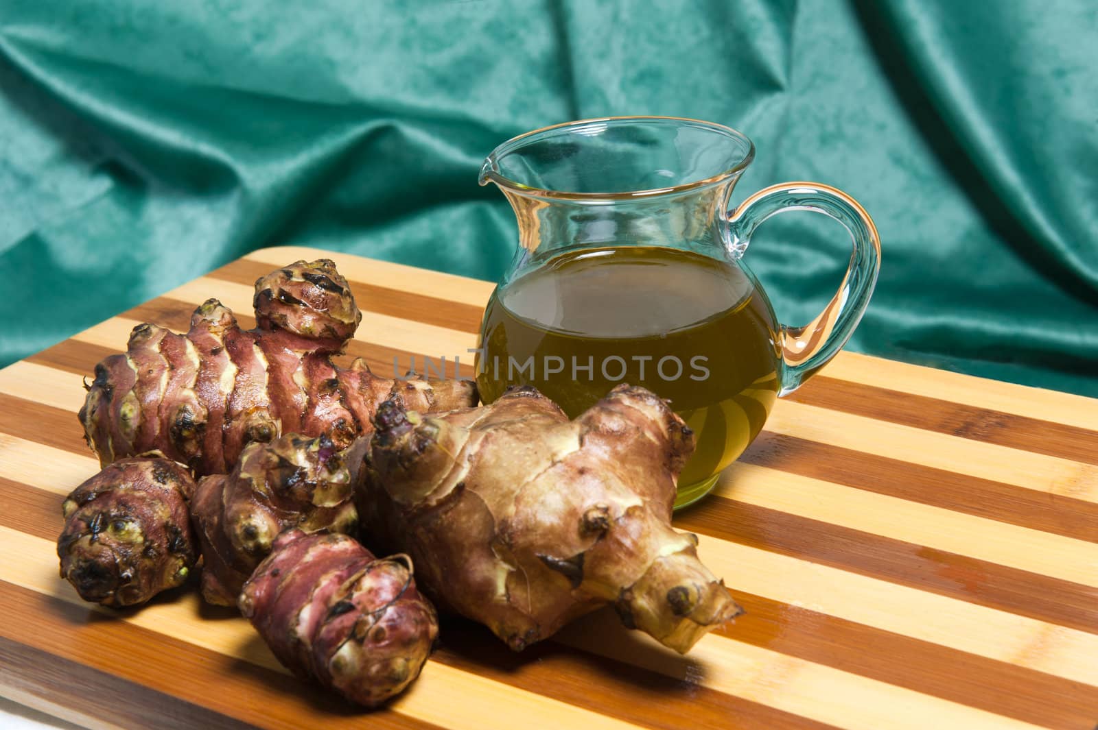 container with fresh ginger and olive oil on chopping bambooo
