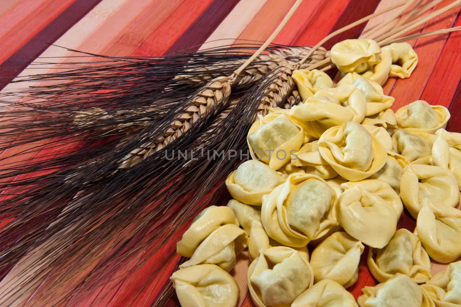 Tortellini and ears of wheat colored bamboo background