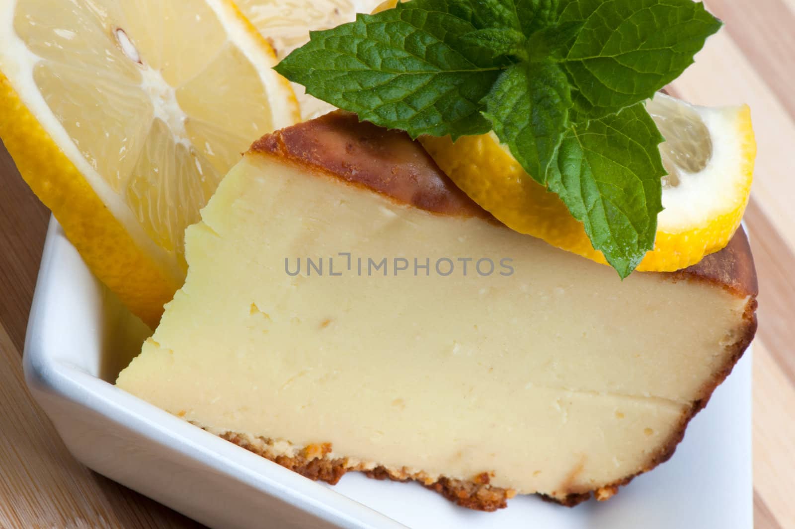 A piece of lemon cake decorated with lemon slices and mint leaves