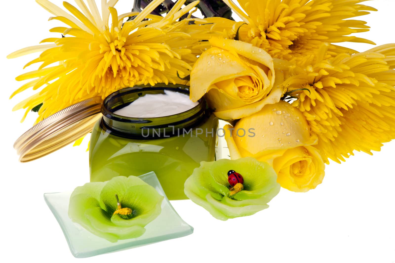 Yellow flowers,candle  and body lotion on a white background