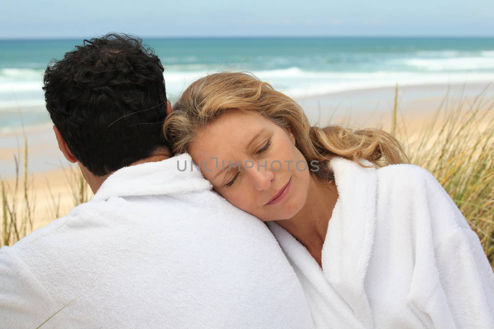 Couple in bathrobe at the beach by phovoir