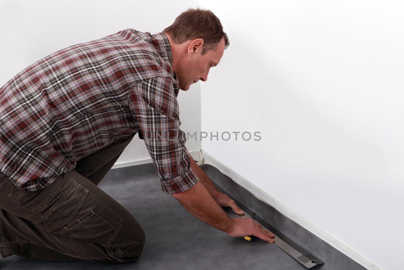 Tradesman laying down linoleum flooring