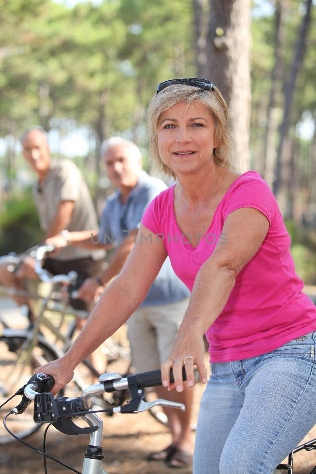 Woman riding a bike with friends in a forest by phovoir