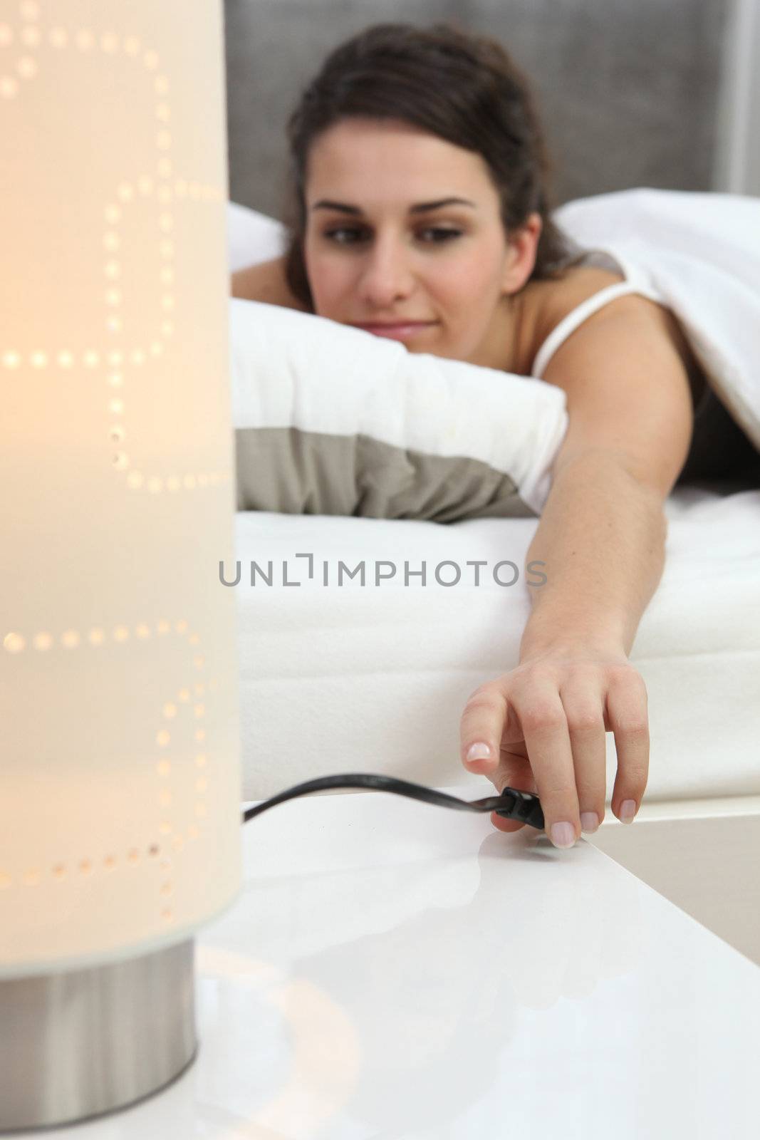 Woman switching off lamp by phovoir