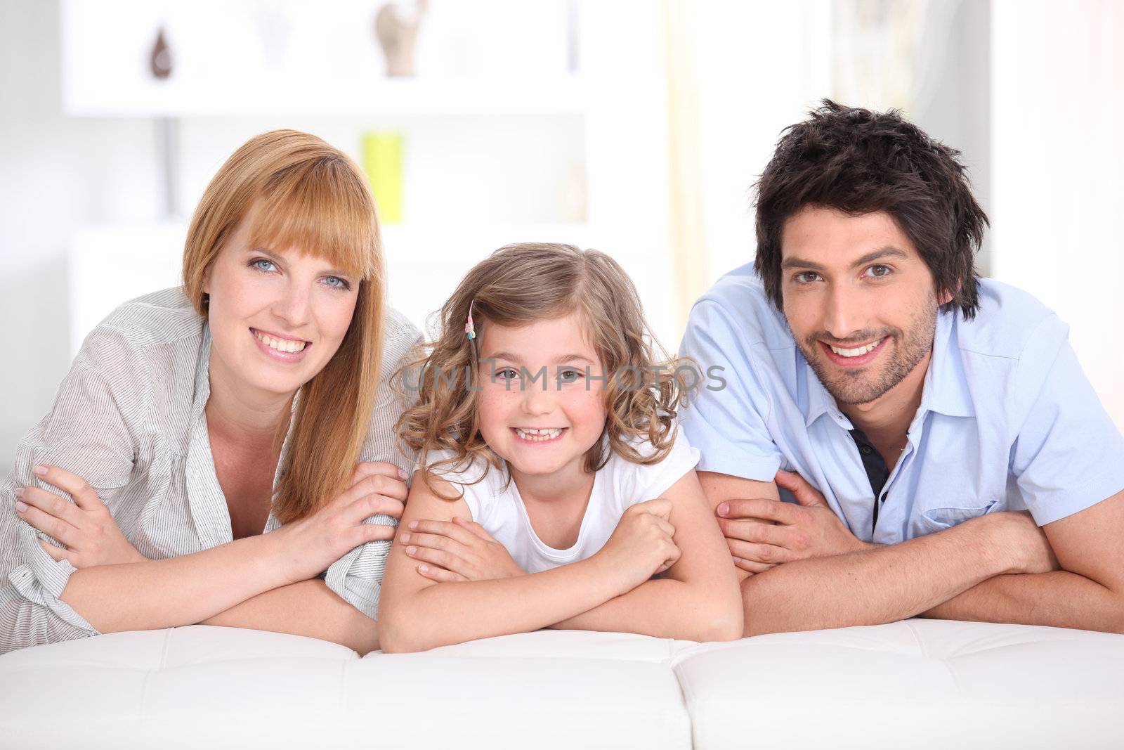 Family laying on bed together by phovoir