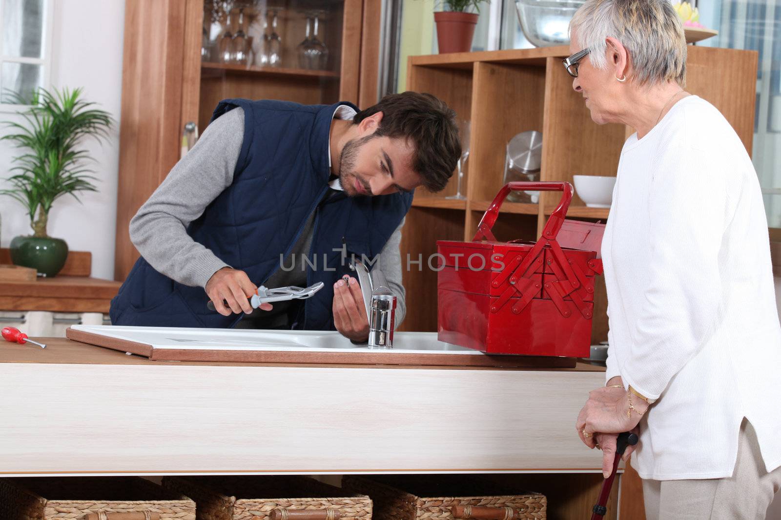 young man fixing faucet older woman by phovoir