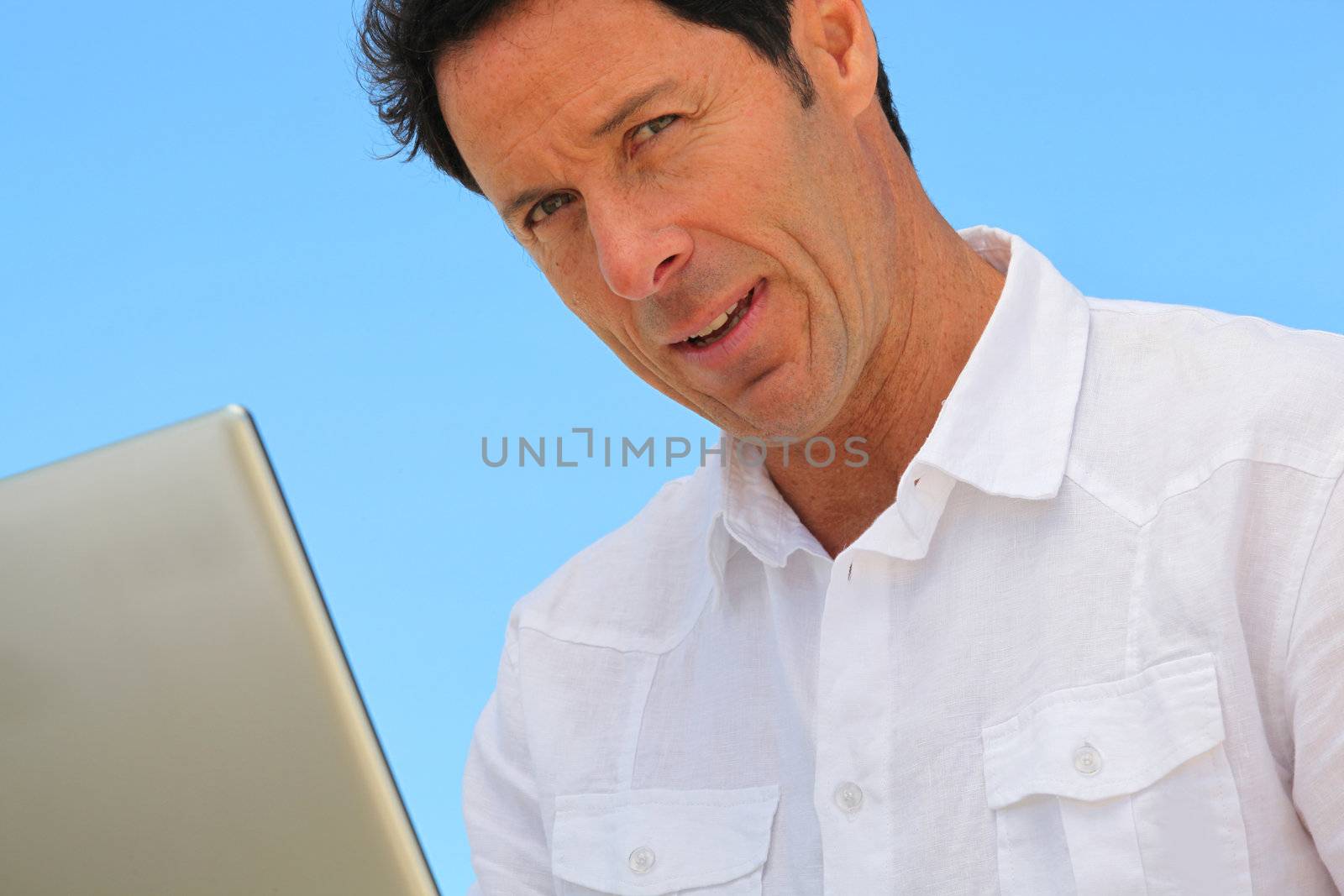 Man on laptop in blue sky