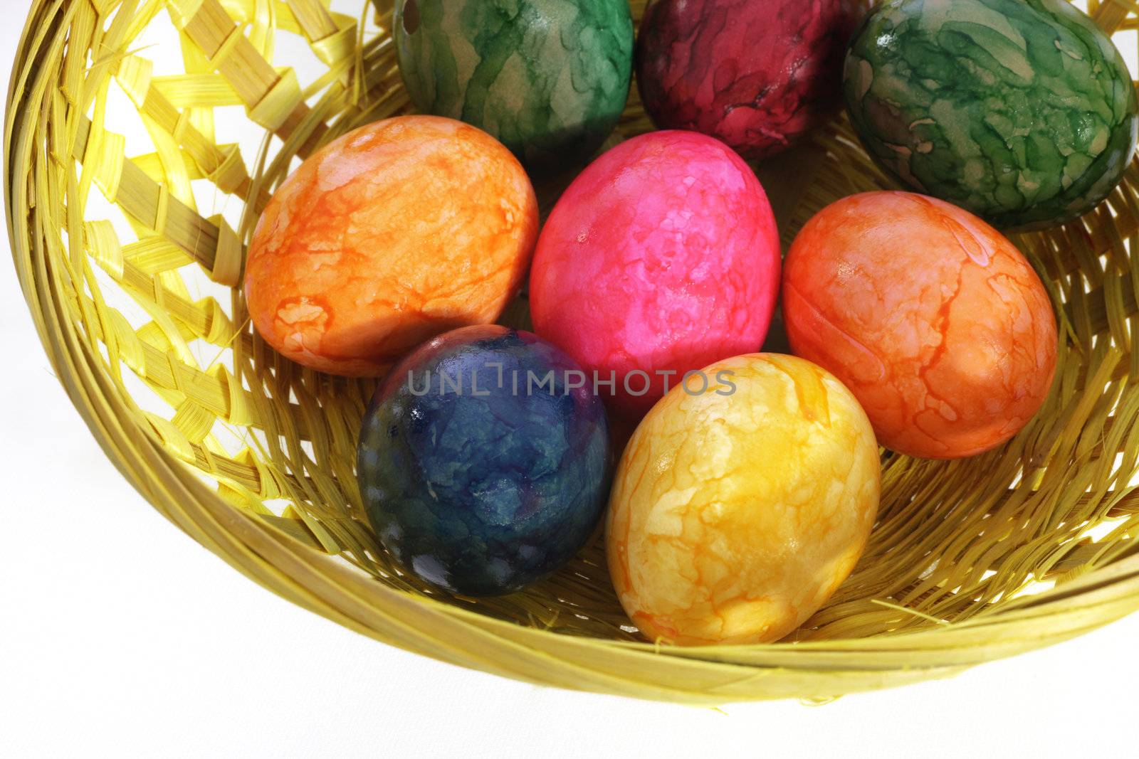 High angle view of a collection of brightly coloured traditional hand painted Easter Eggs in a shallow woven basket