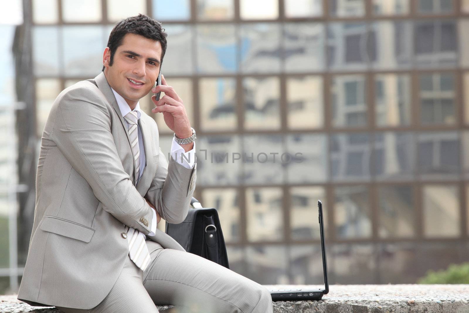 Businessman talking on phone in front of a laptop computer by phovoir