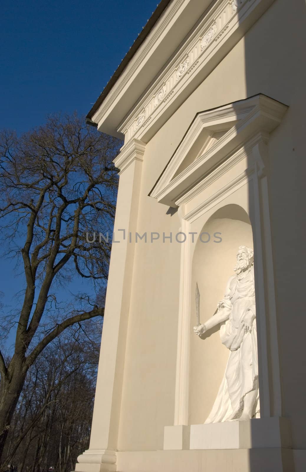 Holy statue holding sword in hand in cathedral arch. Architectural details.