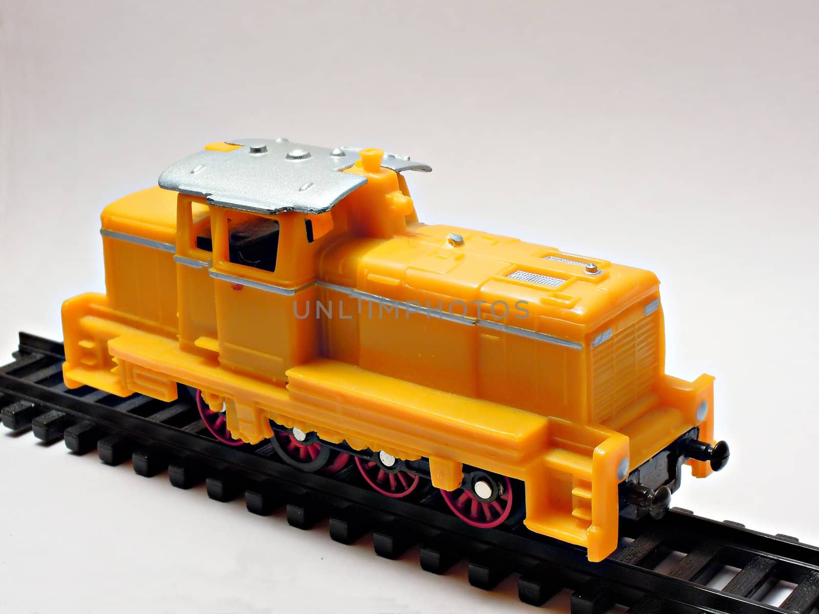 Yellow toy train stays on black railroad and isolated on white background