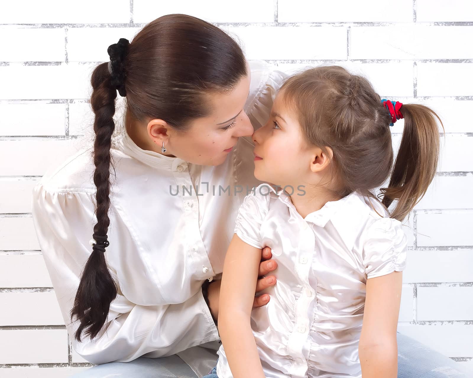 Daughter kissing her mother on a light background