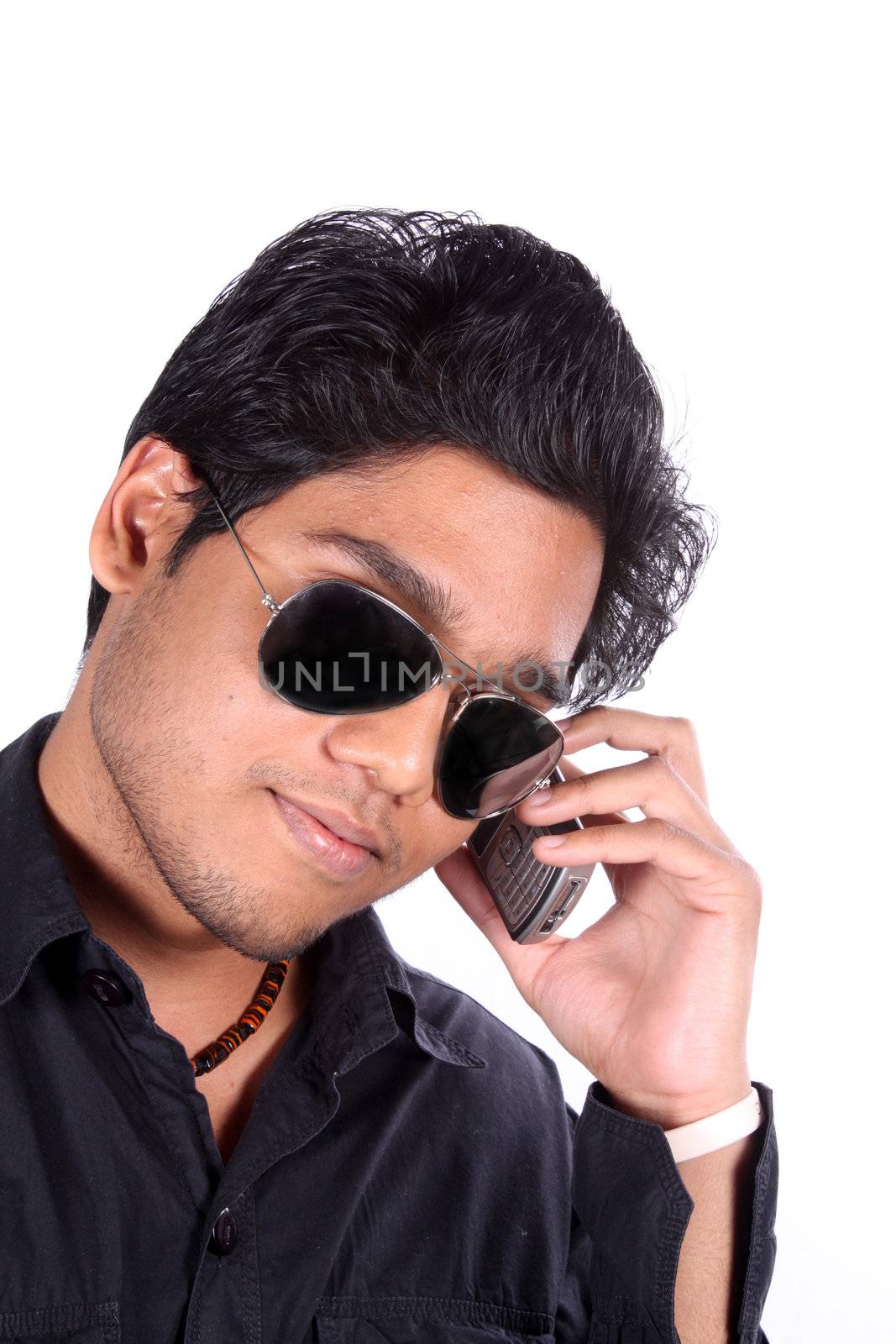 A young Indian guy talking on the cellphone, on white studio background.