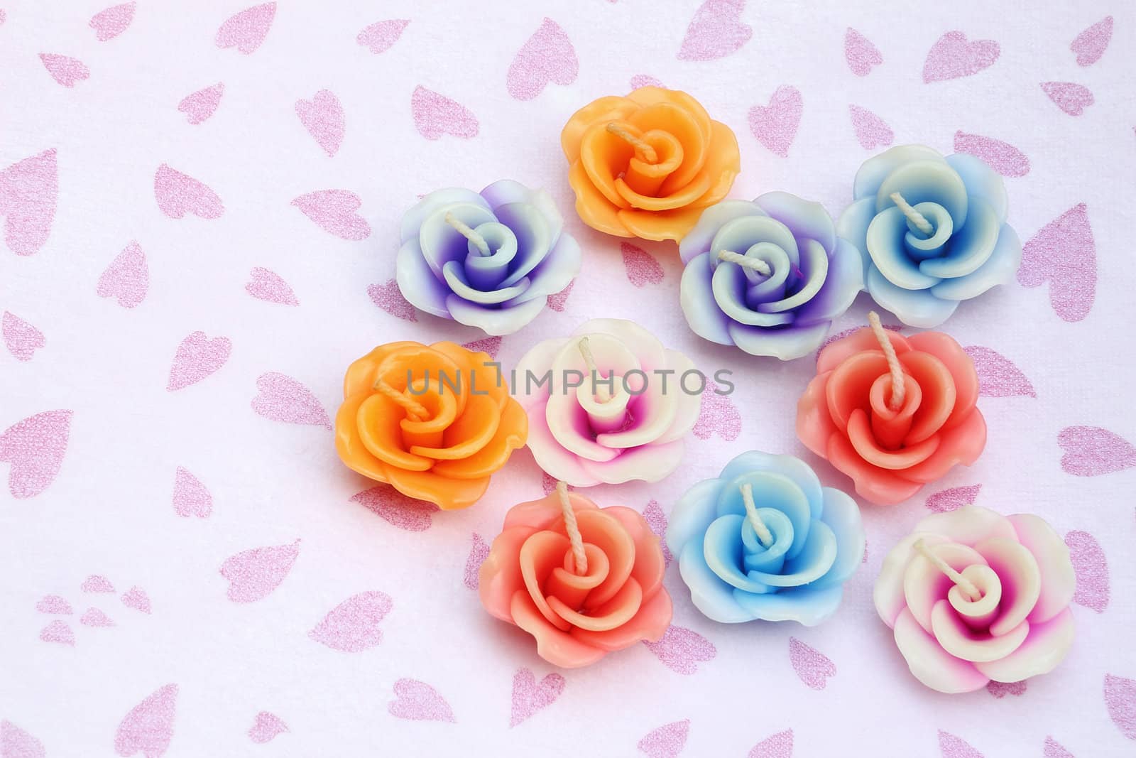 Candles in shape of flower on pink hearts and white background