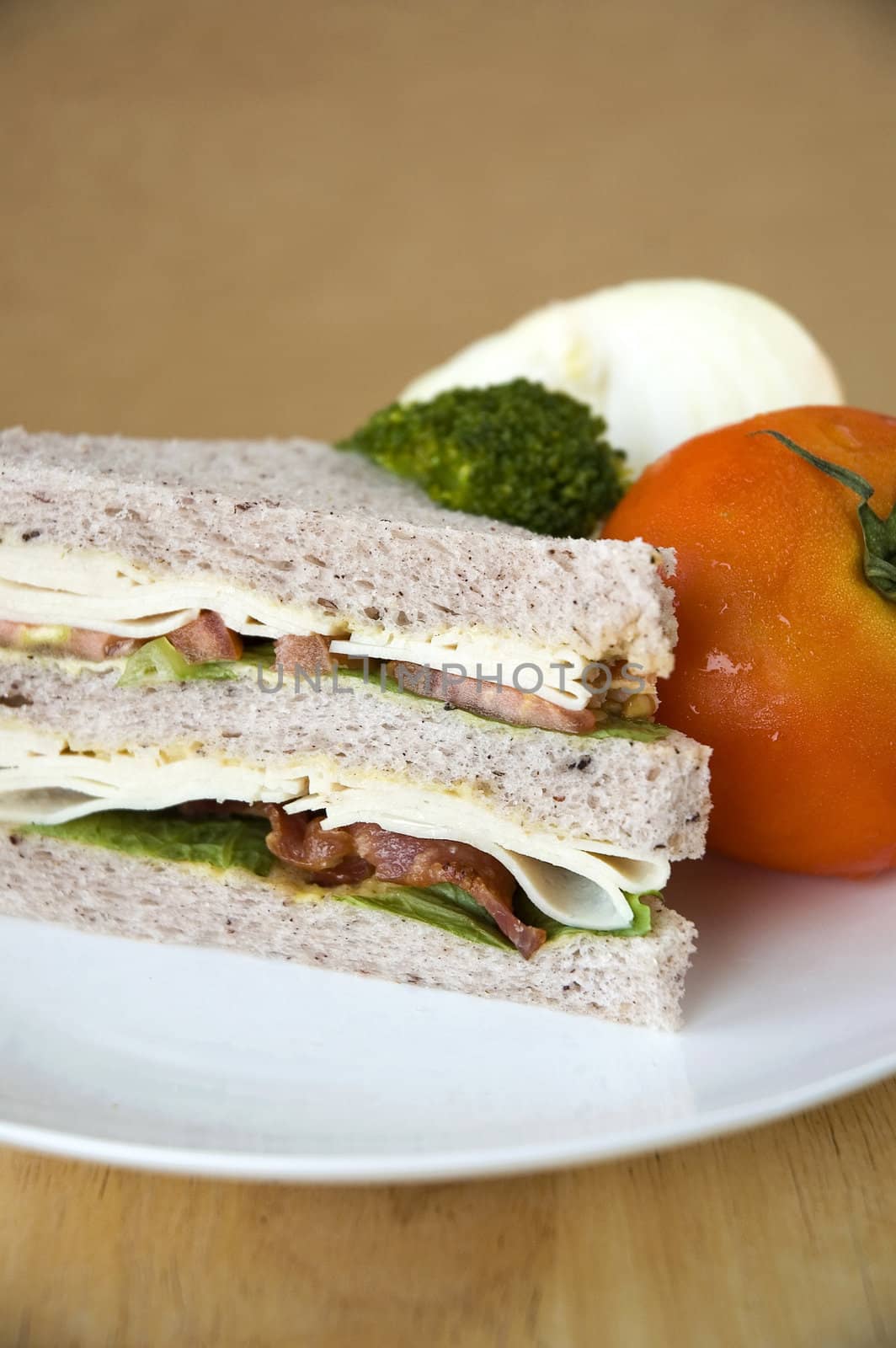 bacon and chicken sandwich with fresh tomato on white plate