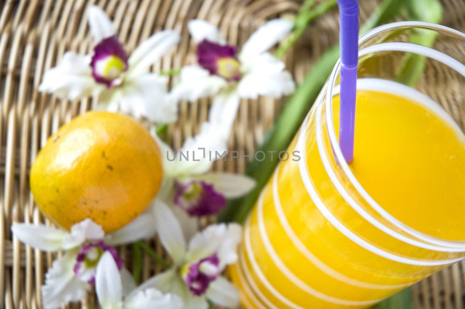 close up glass of orange juice put with fresh orange and orchid