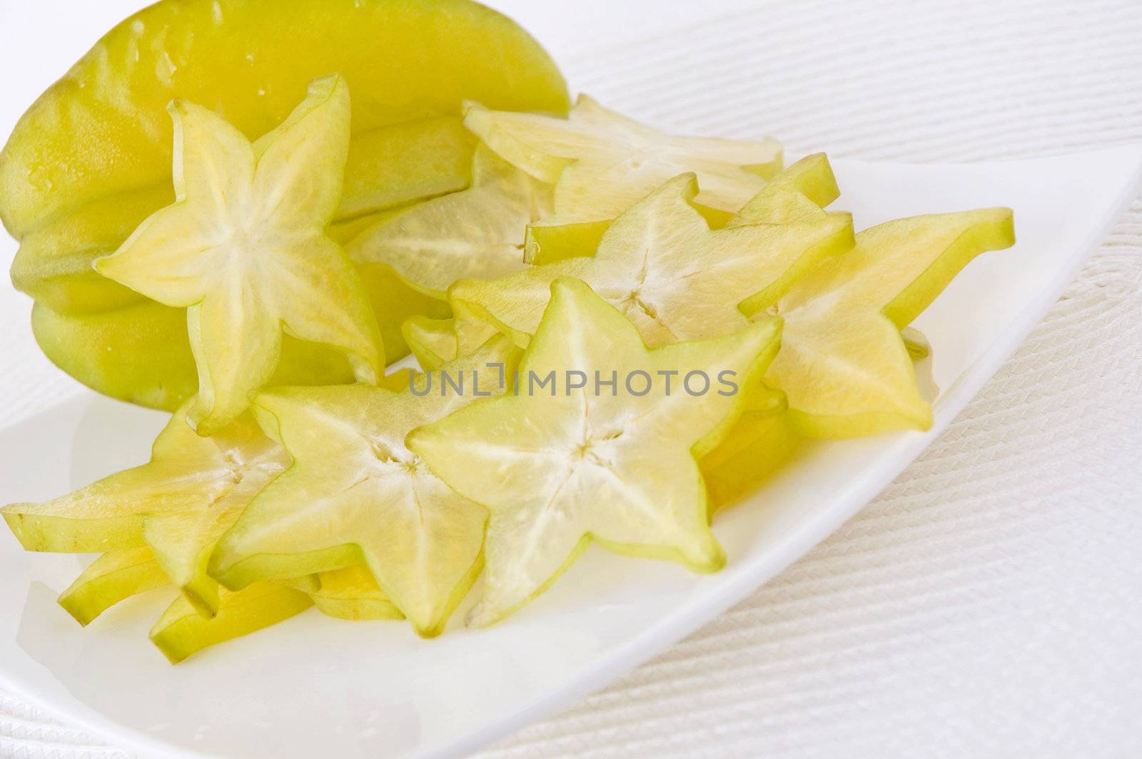 fresh starfruit and sliced starfruit on white plate