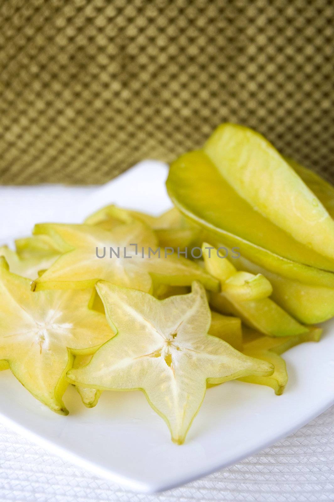 sliced carambola, starfruit serve on white plate with green texture background