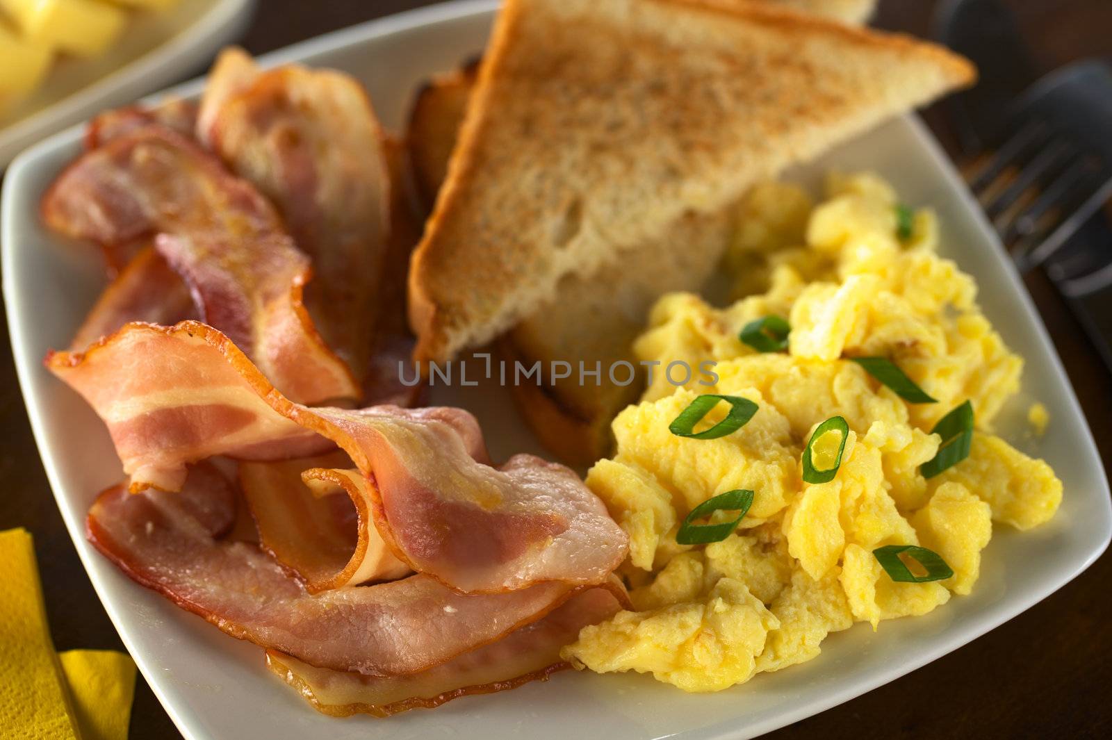 Fried bacon ad scrambled egg with toast bread (Selective Focus, Focus on the lower part of the bacon and the egg)