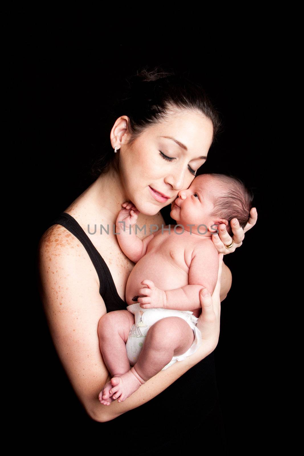 The beauty of motherhood, mother and cute baby. Parent holding infant with care and love, on black.