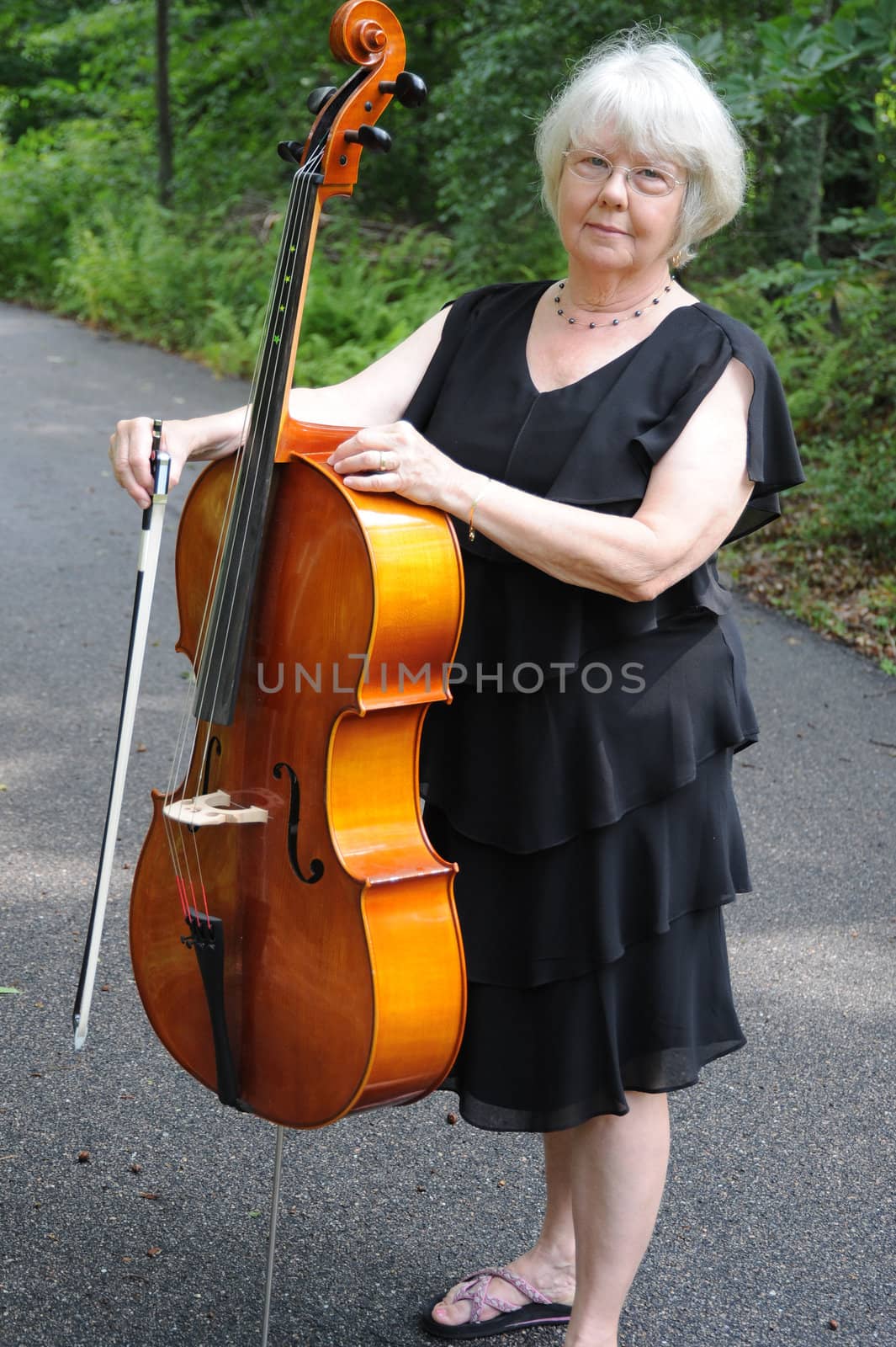 Female cellist standing outside with her cello.