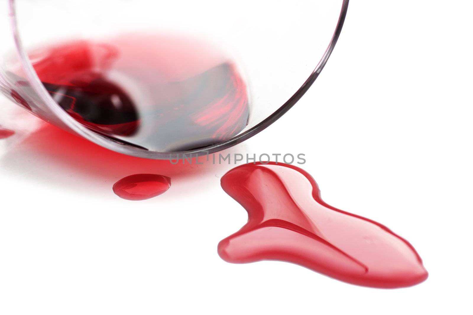 Red wine spilled from glass over white background