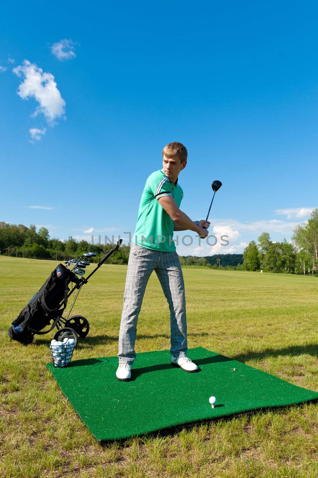 Man about to strike golf ball on green field