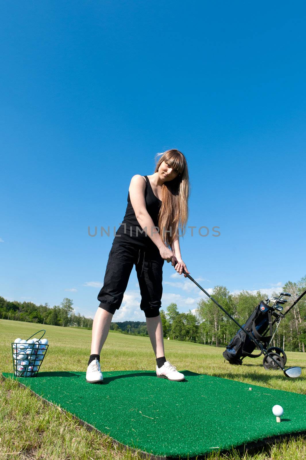 Woman about to strike golf ball on green field