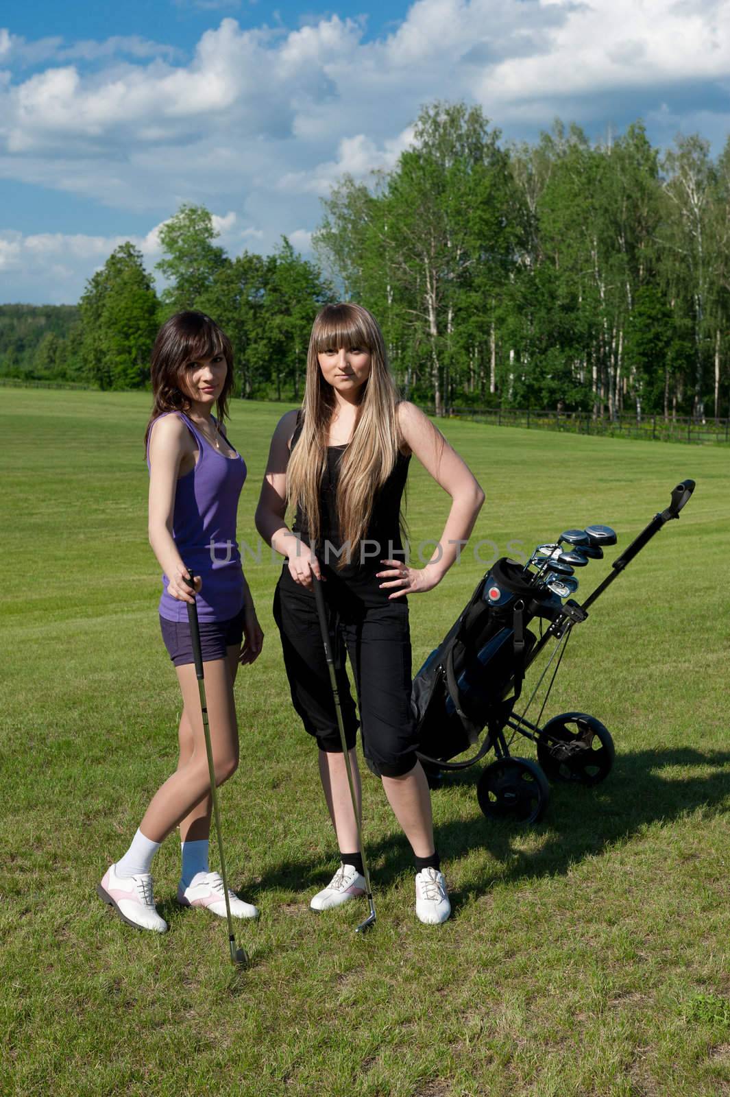 Beautiful girls staying on green golf field