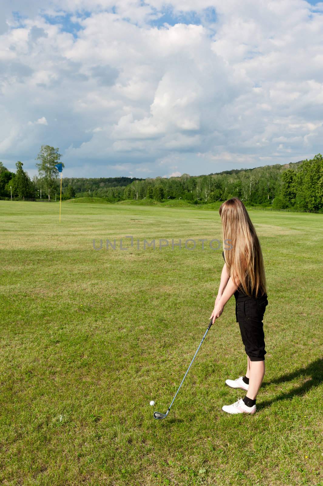 Back view of Caucasion woman swinging golf club.