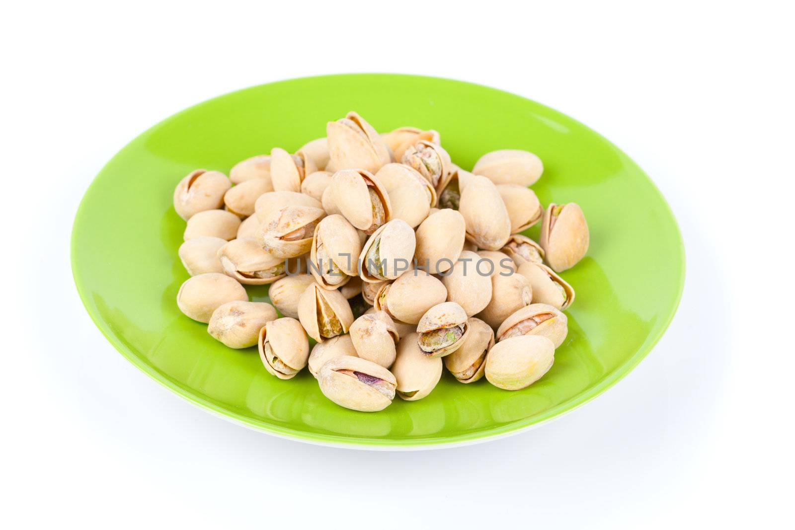 pistachios in a green plate, isolated on white background
